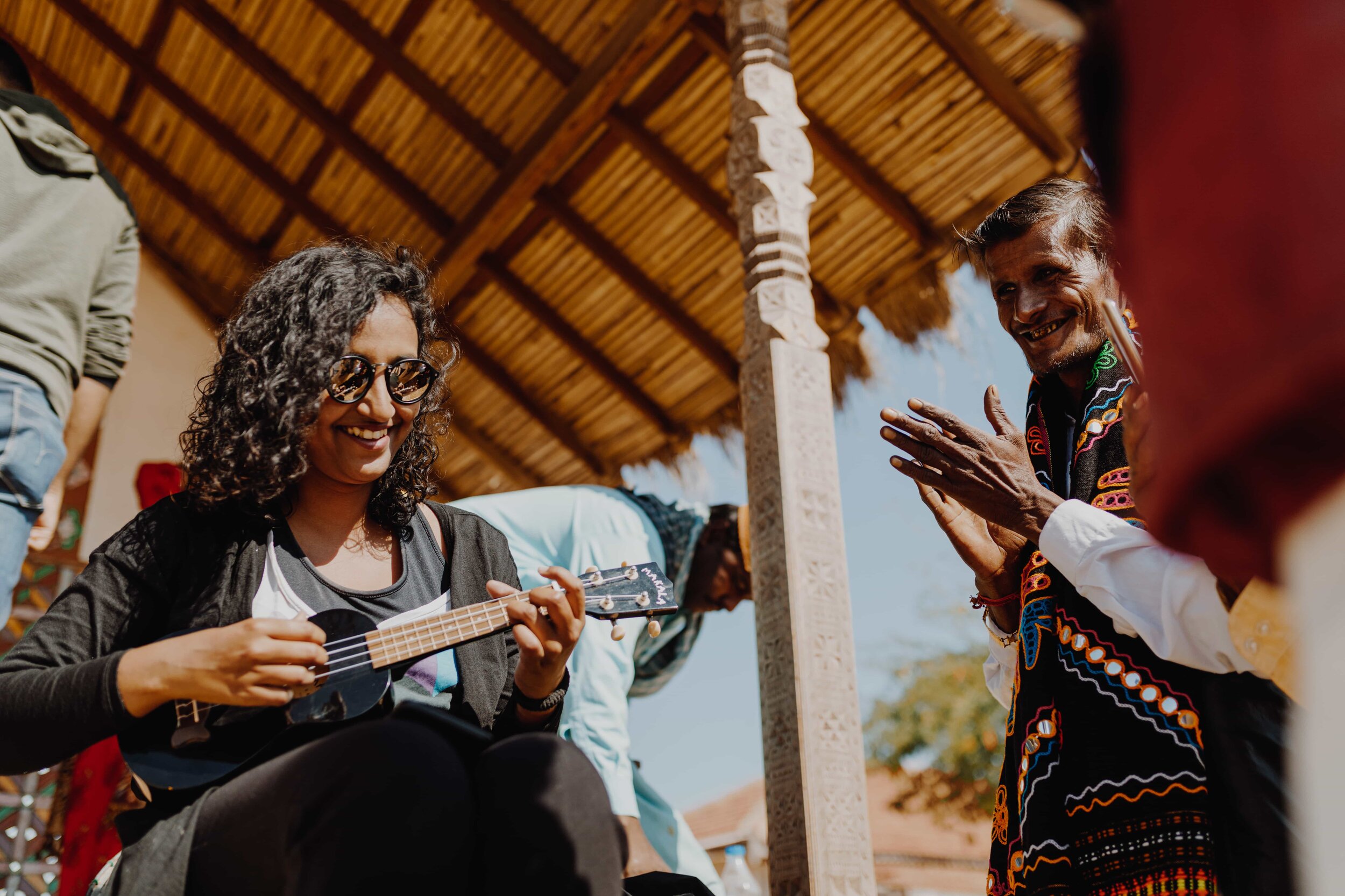Two ExCo community members laughing and playing music together